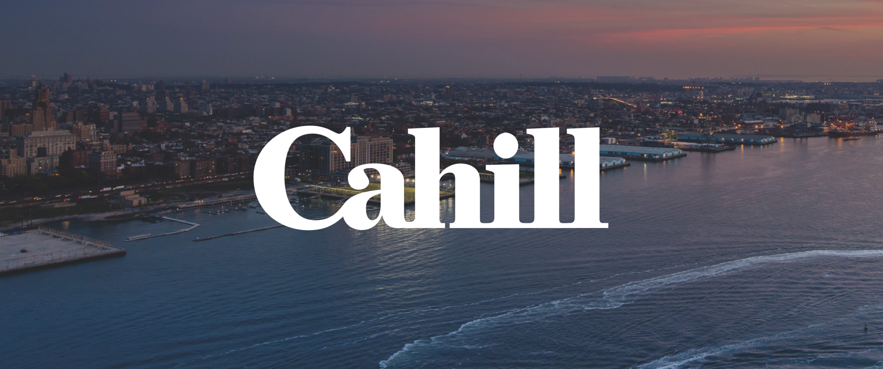 White Cahill Logo over a beach-side city at sunset